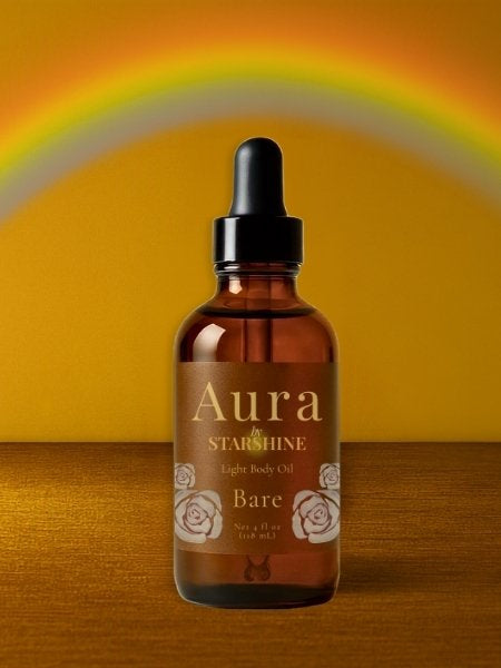 brown bottle of hair oil that says "aura" with a rainbow above it and a brown background