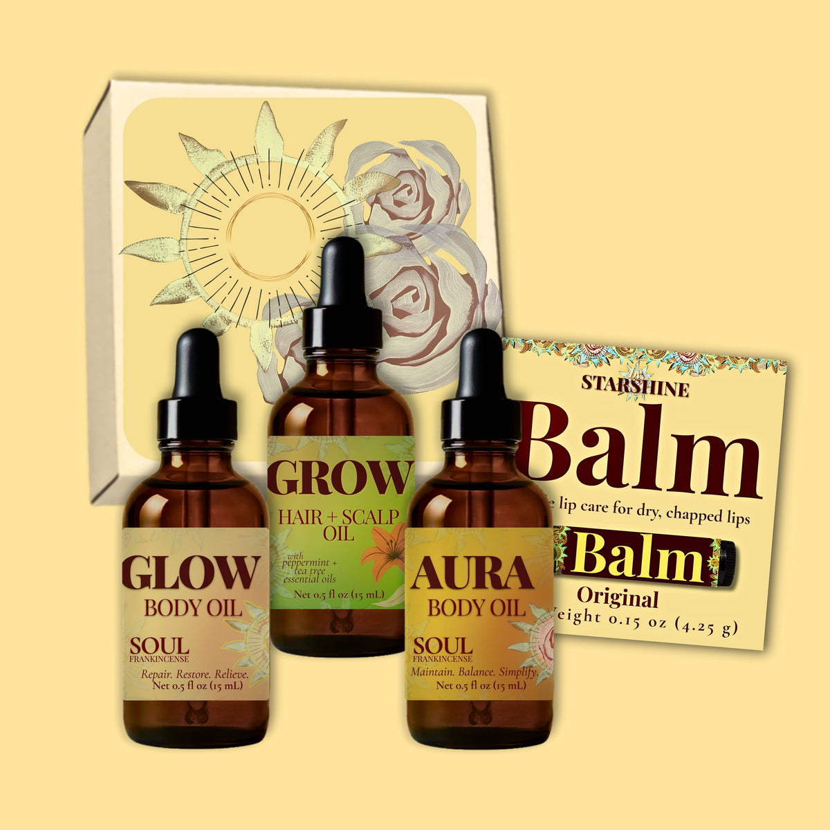 Three amber glass dropper bottles labeled Glow, Grow, and Aura frankincense scented body oil for dry skin with black caps, arranged in front of a white box with floral artwork, alongside a brown balm packet labeled Balm.