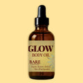 A 1 fl oz amber glass dropper bottle of Glow Body Oil, Bare Unscented, centered against a solid pale yellow background.