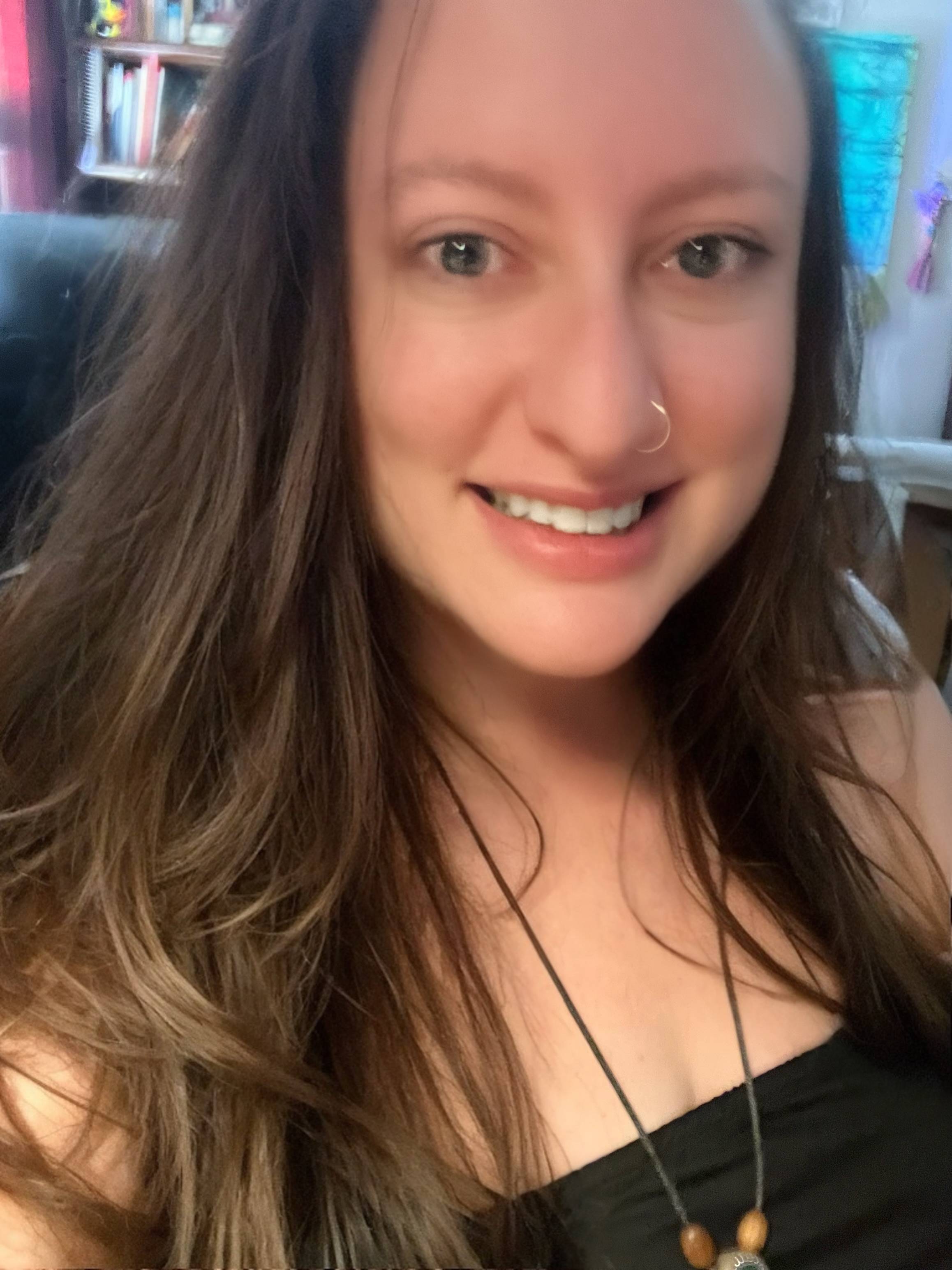 Woman with long brown hair and a black top indoors