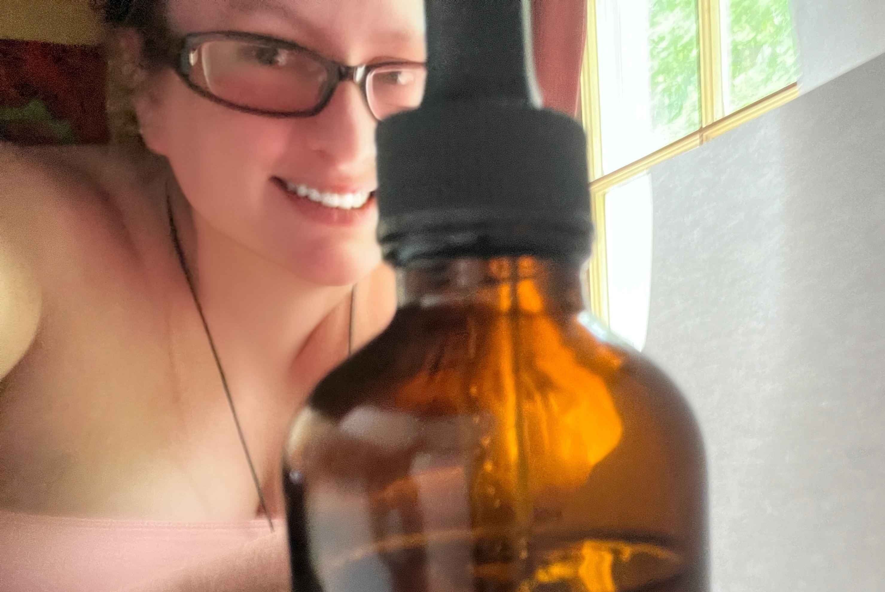 Person holding a brown bottle with a dropper close to the camera